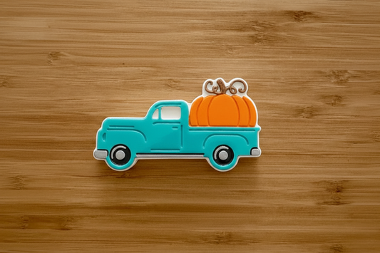 Turquoise truck with orange pumpkin on wood