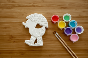 Floral bird bisque piece with paint pots and brushes on wood