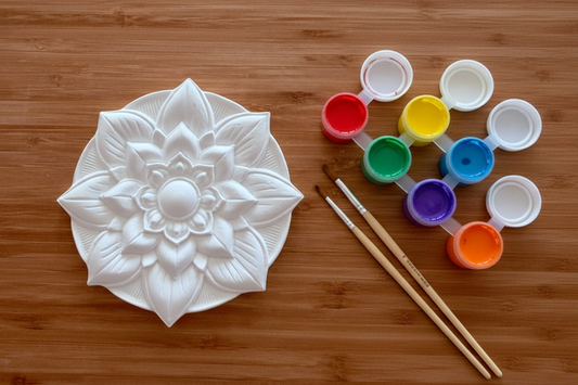 Mandala plate with paint pots and brushes on wood